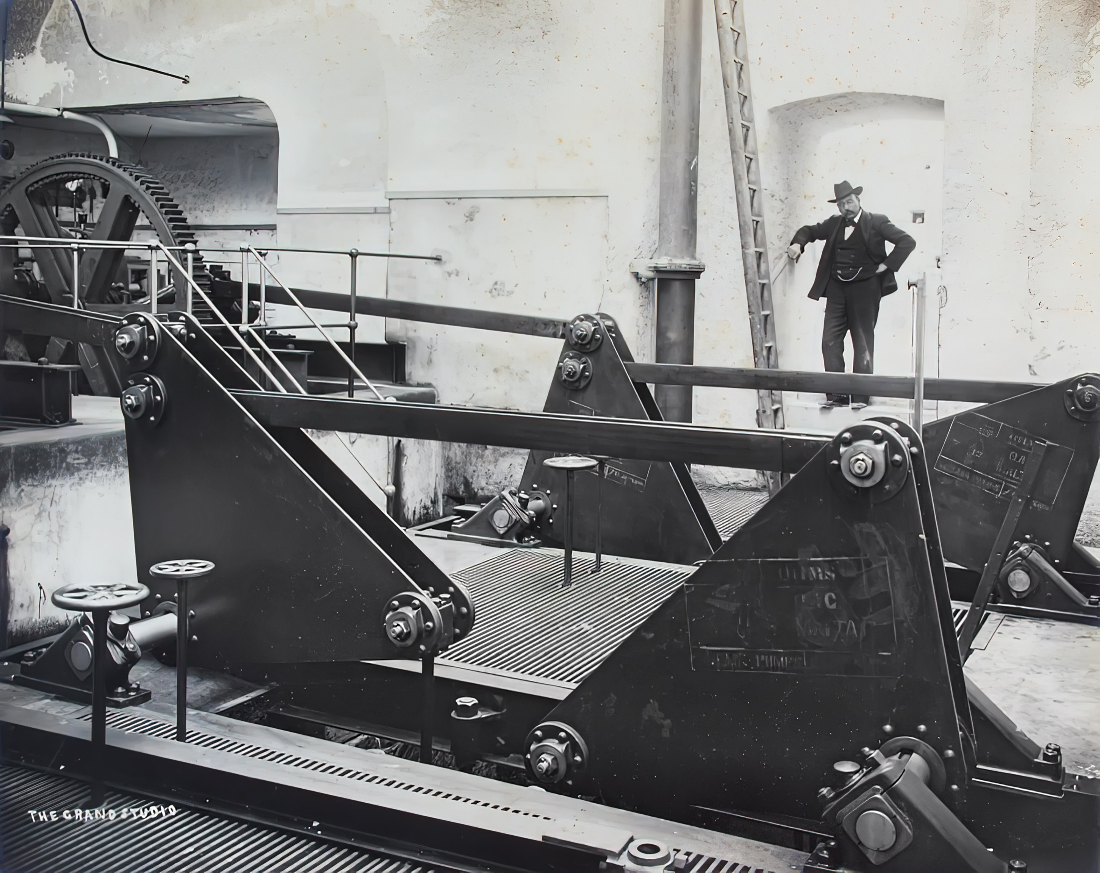 Inside the Gżira Pumping Station: a man stands beside the connecting-rods of the horizontal steam engines